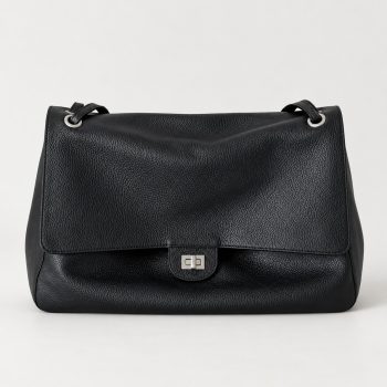 Women's black genuine leather flap shoulder bag shown from front and angled side views, featuring a pebbled texture, silver-tone turn-lock clasp and upper metal eyelet details.