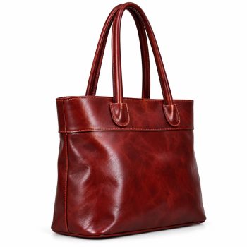 Angled side view of a women's burgundy-red genuine leather tote bag showing its softly structured body, rounded double shoulder handles, smooth-looking leather texture and stitched side panel.