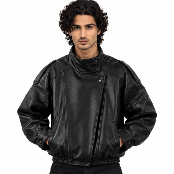 Male model wearing Mizon International men's black oversized genuine leather bomber jacket featuring a high stand-up collar, asymmetrical overlapping front, tonal snap-button details, voluminous sleeves and gathered-looking waistband against a white background.