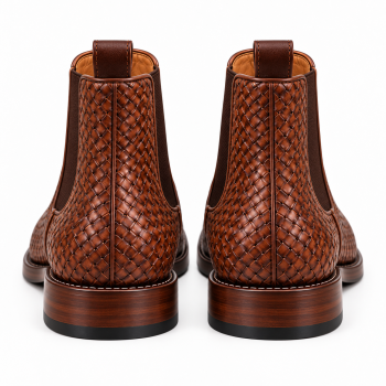 Three-quarter front view of one pair of cognac-brown genuine leather Chelsea-style ankle boots featuring an intricate basket-weave exterior, dark brown side panels, rear pull tabs, rounded almond-shaped toes, and low block heels on a white background.